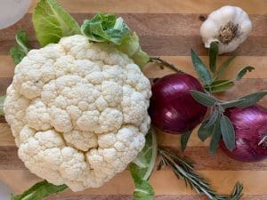 Ingredients for Roasted Cauliflower with Sage and Rosemary on a cutting board