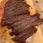 Grilled flank steak sliced on cutting board