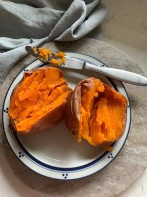 One baked sweet potato sliced open on a plate
