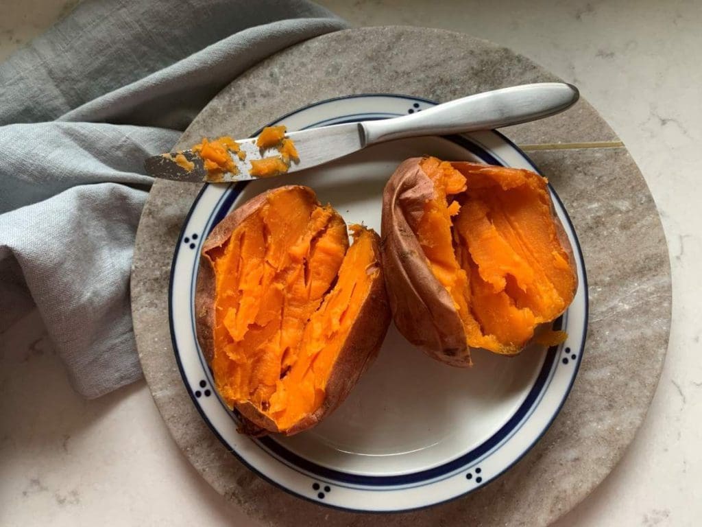 One baked sweet potato sliced open on a plate