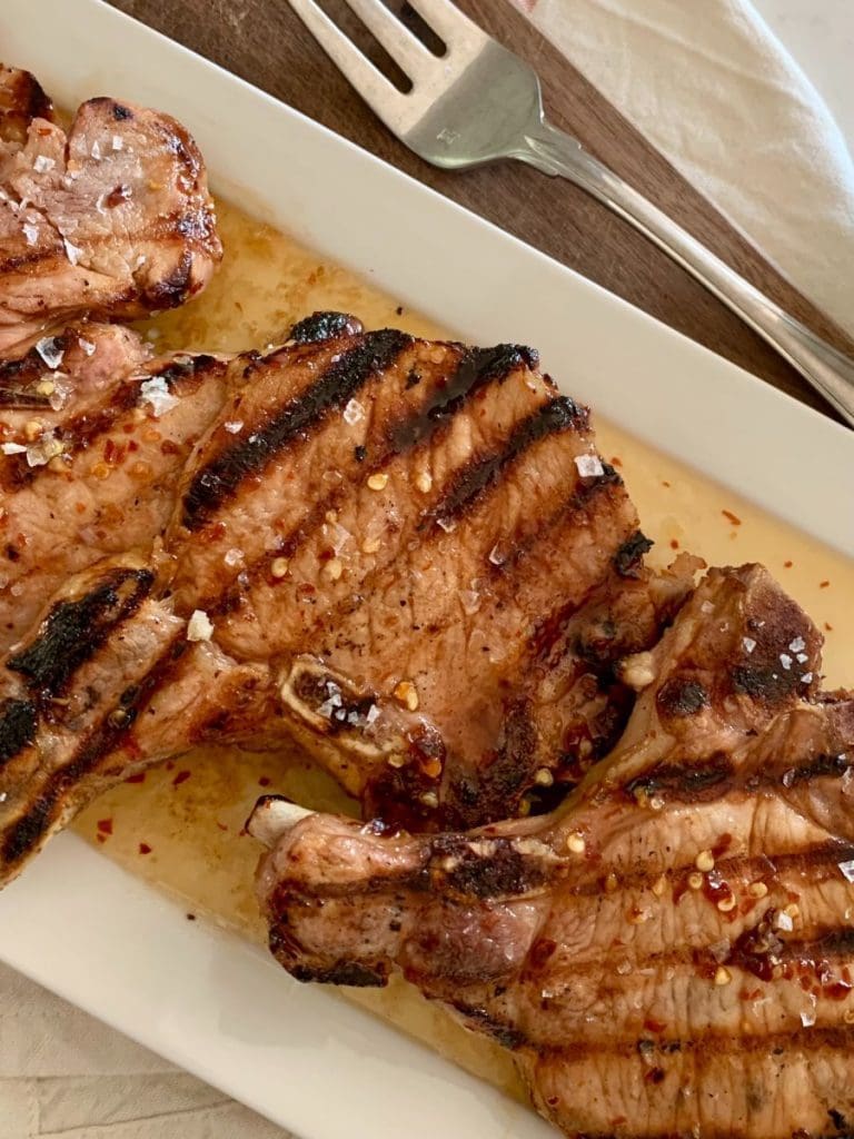 Grilled pork chops on a white platter