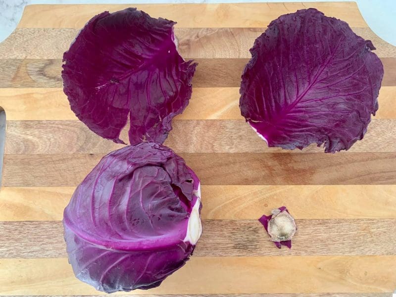 Red cabbage with top leaves and stem removed on a cutting board